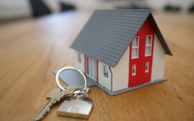 Toy house with red door on desk with set of keys