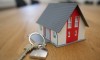 Toy house with red door on desk with set of keys